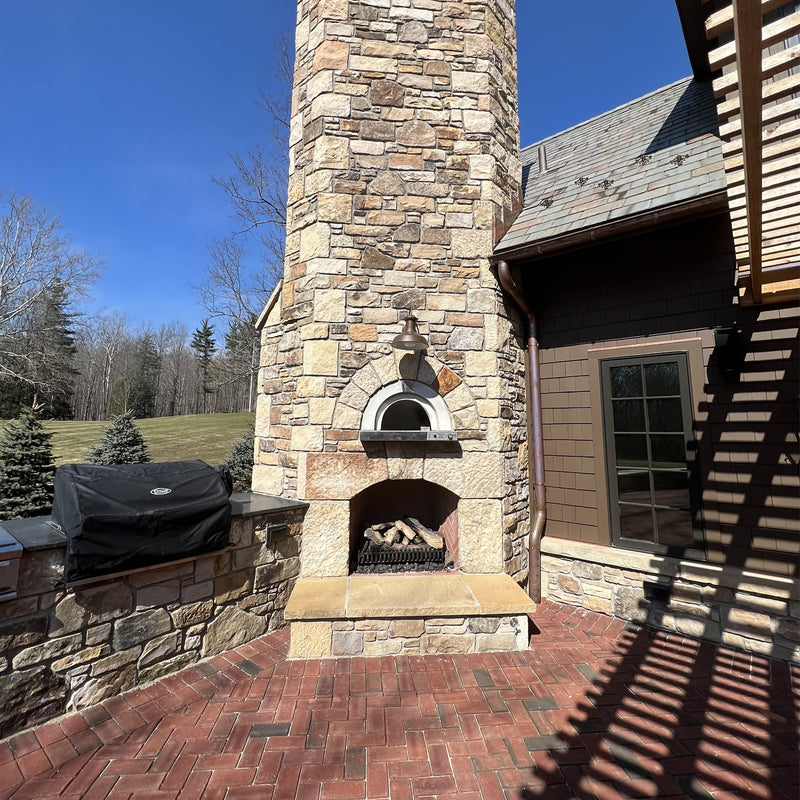 HPC Di Napoli pizza oven finished in natural stone with a tall stone chimney