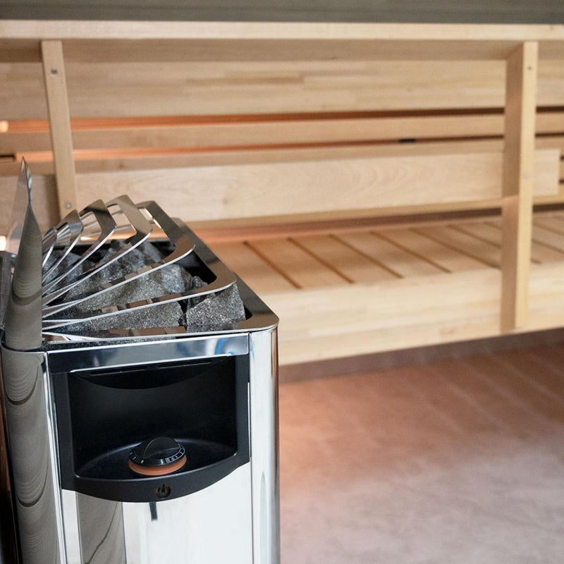 Harvia The Wall SWS80 sauna heater in polished stainless steel mounted on a wall, featuring control knobs and heating elements.