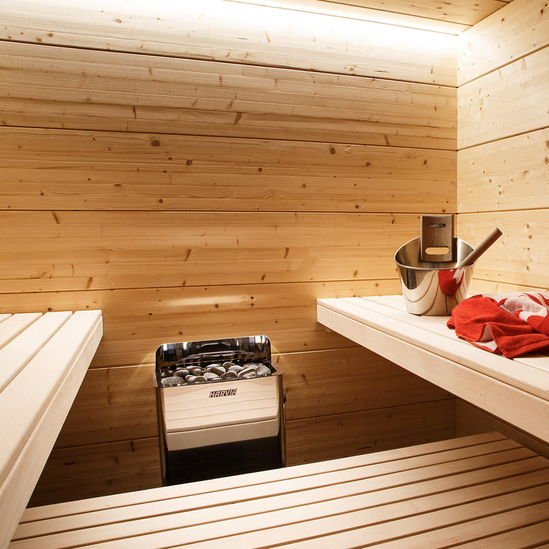 Harvia The Wall stainless steel sauna heater installed in a light spruce sauna