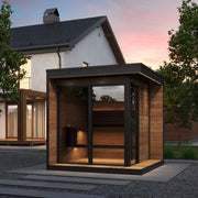 SaunaLife GL6 outdoor sauna with panoramic glass front installed in a backyard at sunset