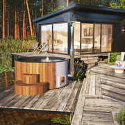 SaunaLife S4N wood-fired hot tub on a lakeside deck beside a modern cabin