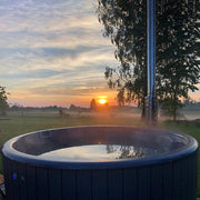 SaunaLife Model S4N wood burning hot tub with wooden exterior and open seating, set outdoors on a natural landscape.