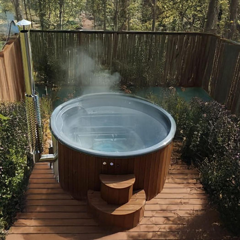 Wood-fired SaunaLife Model S4N hot tub with wooden exterior and built-in seating, designed for outdoor relaxation and natural heating.